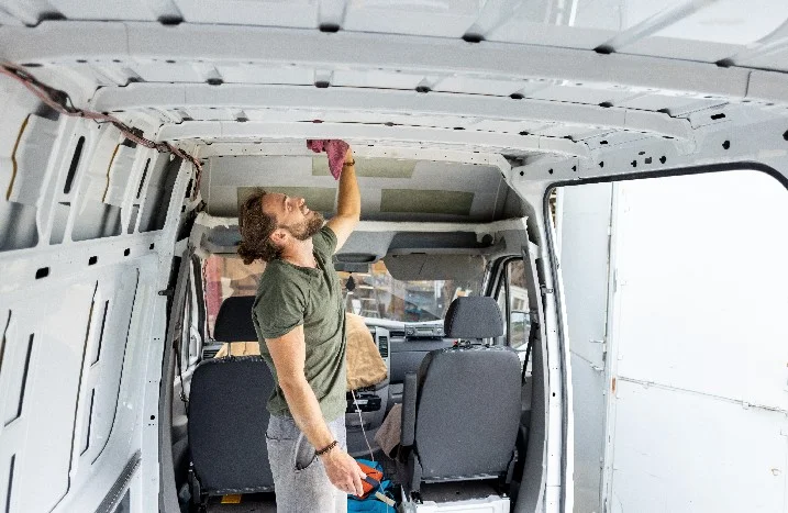 Person reinigt Dach eines Transporters